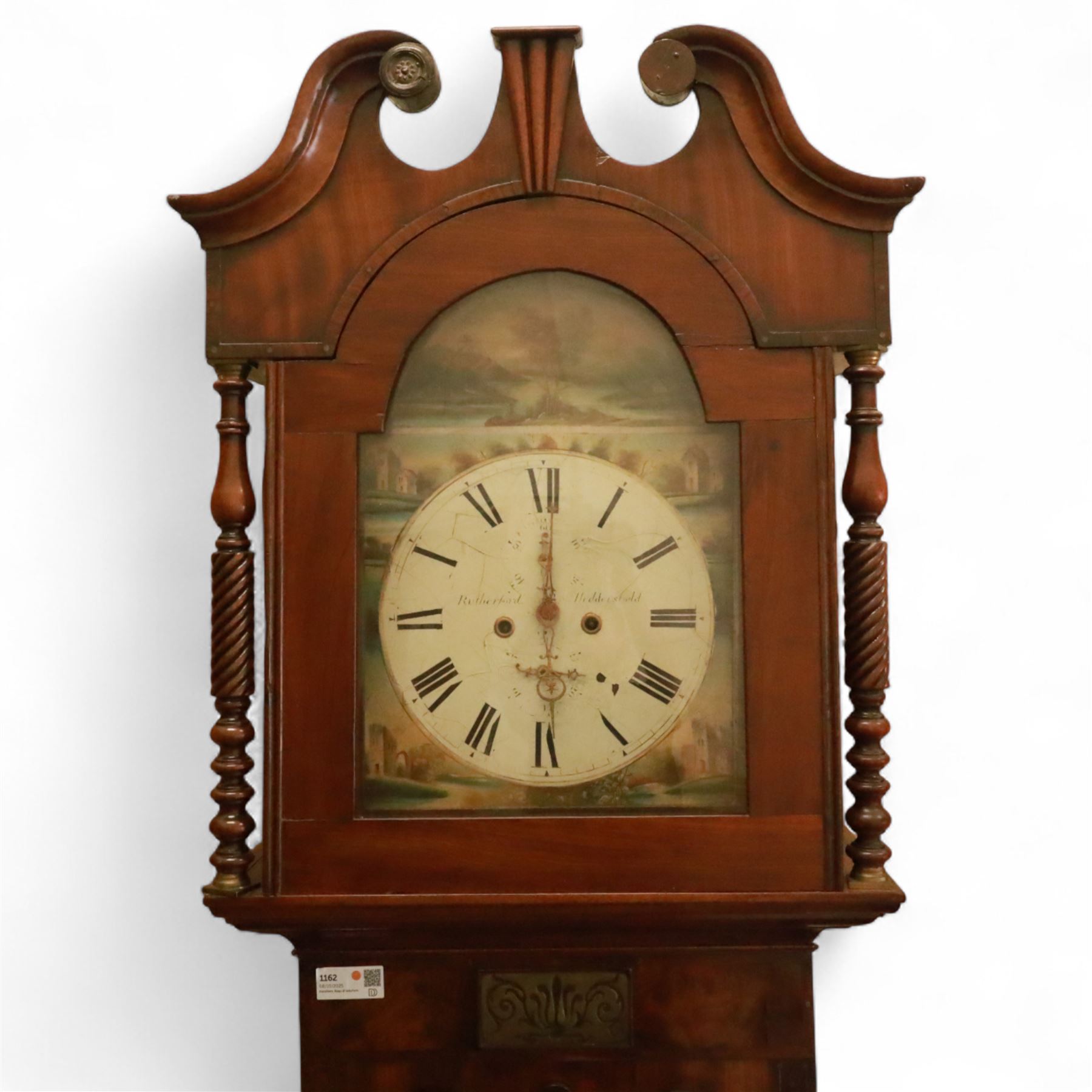 George Rutherford of Huddersfield- 8-day mahogany longcase clock c1880, with a swan neck pediment and turned patera, hood with shaped back splats and a break arch hood door flanked by ring turned pilasters, trunk with conforming recessed pilasters and a short wavy-topped trunk door, on a broad plinth raised on bracket feet, fully painted dial with matching pastoral depictions to the spandrels and break arch, with makers name, Roman numerals, subsidiary seconds and date dials and matching stamped brass hands, dial pinned via a falseplate to a rack striking movement striking the hours on a bell (bell missing). With pendulum, no weights.
