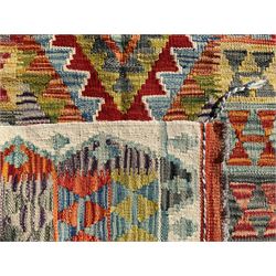 Afghan Chobi Kilim ivory ground rug, central geometric design consisting of stacked lozenge medallions in shades of red, green, and blue, flanked by multicoloured triangular motifs, guarded by zigzag patterns in contrasting tones