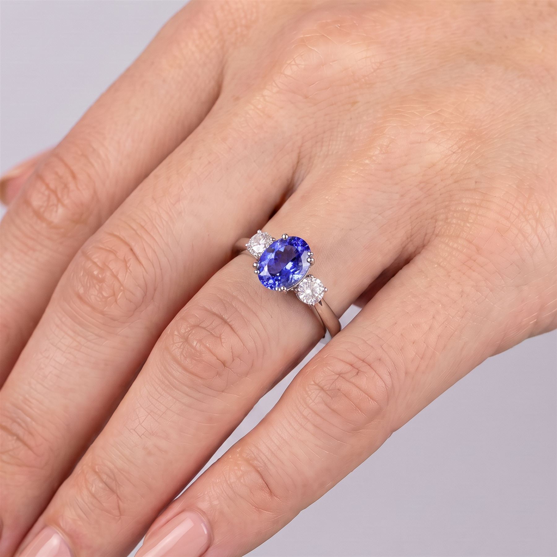 Platinum tanzanite and diamond three stone ring, single oval cut tanzanite of approx 3.55 carat, with a round brilliant cut diamond set either side, total diamond weight approx 0.80 carat