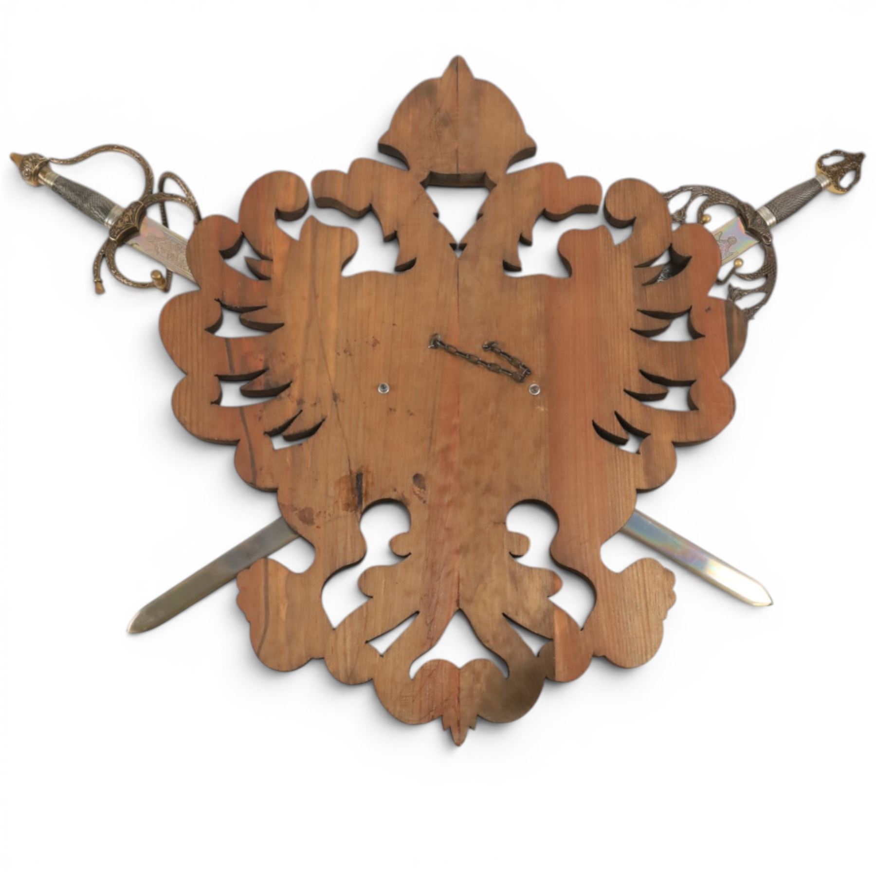 Carved wooden wall plaque, decorated with foliate scrolls, with two reproduction swords attached, together with five other wooden plaques with foliate scrolls and shields