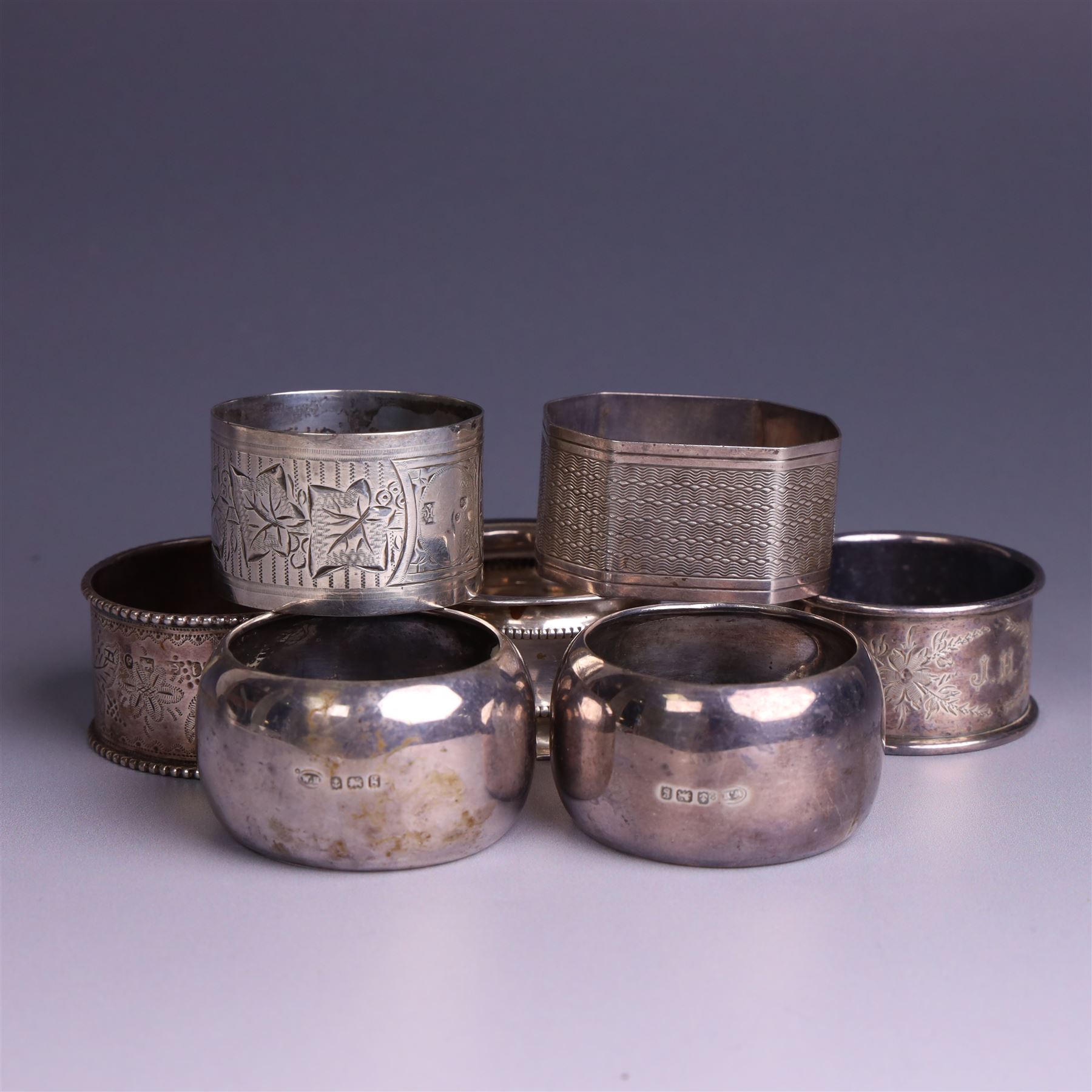 Seven silver napkin rings, of varying design and each with engraved initials, all hallmarked
