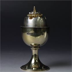 Late 20th century silver-gilt novelty surprise egg by Anthony Gordon Elson, the egg cup containing a  removeable shell, lifting to reveal a parcel gilt egg basket beneath, hallmarked Anthony Gordon Elson, London 1979, H11cm