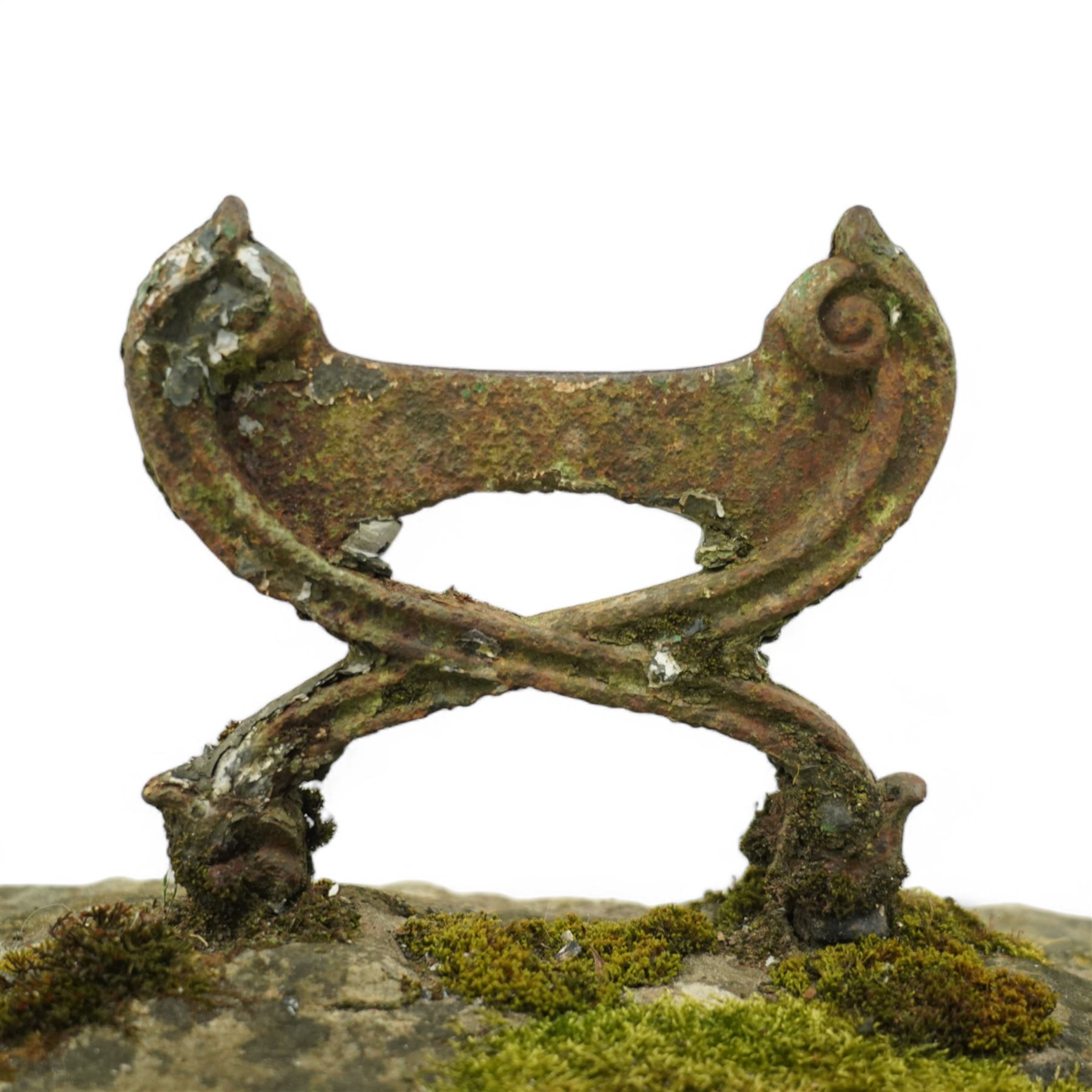 19th century cast iron boot scraper, with scrolled upright mounts, set into a rectangular moss-covered stone base