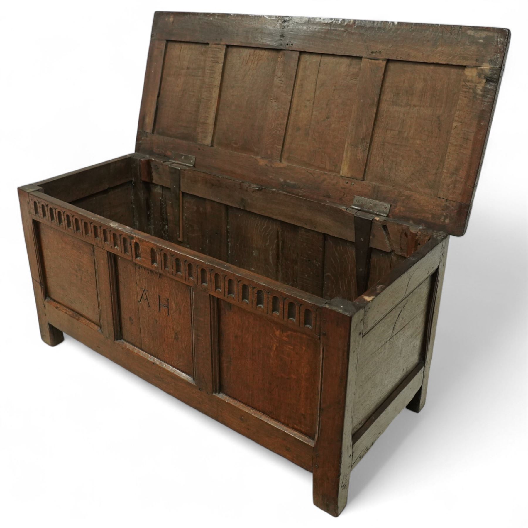 18th century and later oak coffer, the hinged plank top above a panelled front carved with lunette frieze, plain stiles and rails, carved with initials ‘AH’, pegged construction throughout