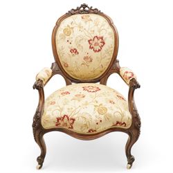 Victorian Ladies and Gentleman's carved walnut drawing room chairs, each with shaped cresting rail carved with scrolls and flowerheads, upholstered in pale gold floral fabric, raised on foliate-carved cabriole supports terminating to brass and ceramic castors