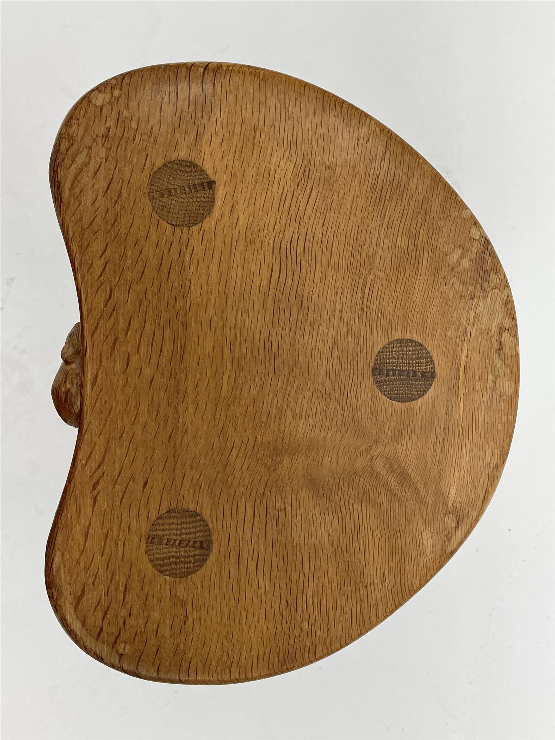 'Mouseman' oak three legged stool with dished kidney shaped seat, tapered octagonal supports, with carved mouse signature, by Robert Thompson of Kilburn 