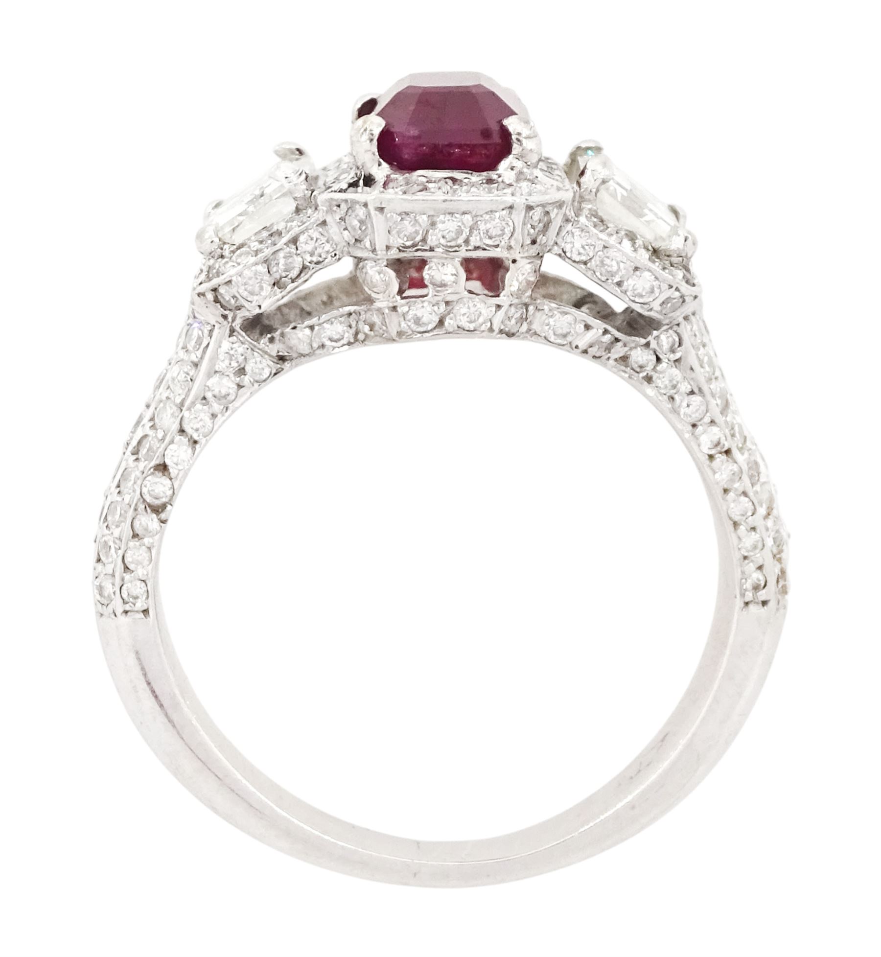 18ct white gold ruby and diamond trilogy ring, single emerald cut ruby of approx 1.85 carat, with a single emerald cut diamond set either side, all surrounded by round brilliant cut diamonds, the shoulders set with three rows of round brilliant cut diamonds, principal two emerald cut diamonds approx 1.10 carat