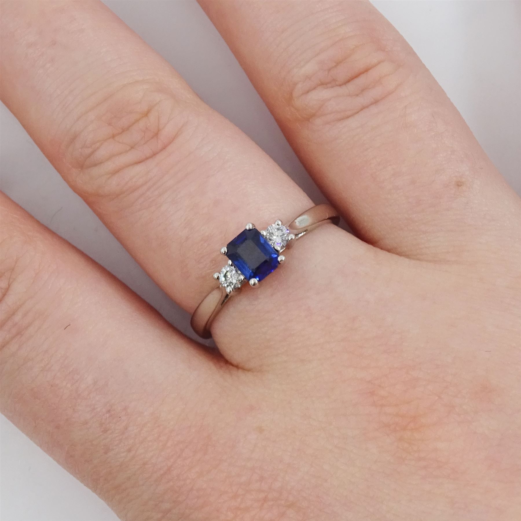 Platinum three stone emerald cut sapphire and round brilliant cut diamond ring, hallmarked, sapphire approx 0.50 carat, total diamond weight approx 0.15 carat