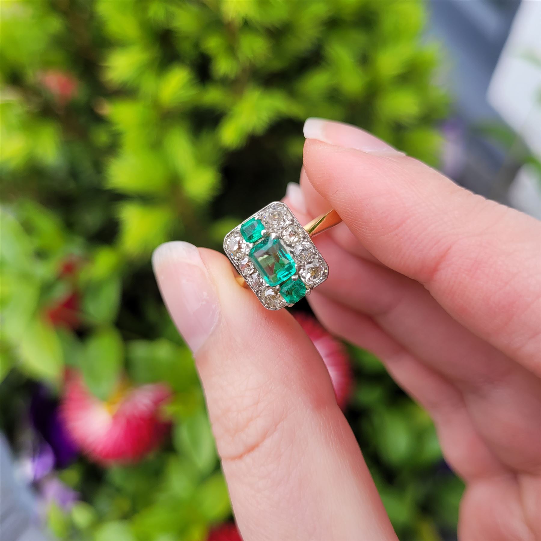 Early 20th century gold emerald and diamond panel ring, three octagonal cut emeralds, with four old cut diamonds set either side, stamped 18ct Plat, total diamond weight approx 0.85 carat