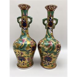 Pair of early 19th century Miles Mason vases, the baluster bodies with tall slender necks supporting twin stylised trunk handles with rings, decorated with Chinese dragons, butterflies, and blossoming flowers against a gilt ground, with spurious Chinese marks beneath in iron red, H27.5cm