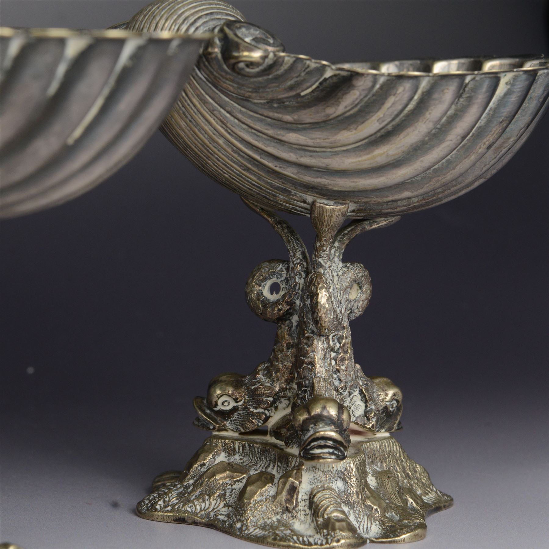 Pair of Victorian silver plated comports, with clam shell bowls supported by three dolphins upon a rocky base, H12cm