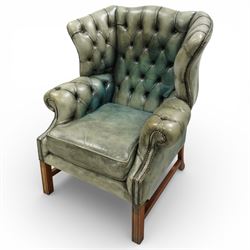 Georgian design mahogany framed wingback armchair, upholstered in rustic pale green buttoned leather with loose seat cushion, raised on square supports united by H-stretcher