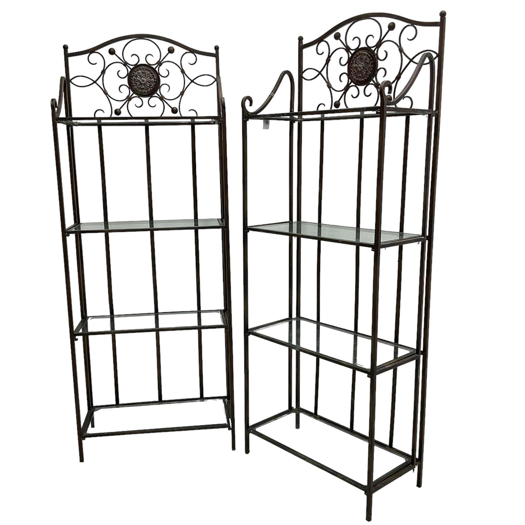 Pair of wrought metal conservatory plant stands, raised back with scrolling design, each fitted with three glass shelves