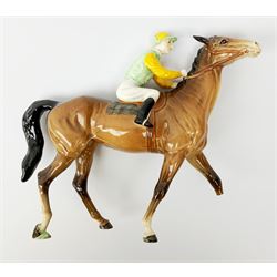 A Beswick jockey on horseback, the jockey in green and yellow silks upon walking chestnut horse, with printed mark beneath, (a/f), H21.5cm.