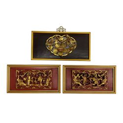 Set of three early 19th century Chinese carved gilt wood panels of rectangular form, carved and pierced in high relief, to include a pair on red ground decorated with figures in scrolling floral branch border, and larger example on deep red brown ground decorated with flowers and Oriental style metal hanging fitting, all in gilt frames largest W32cm 