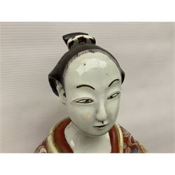 Large Japanese Imari porcelain figure, modelled as a Bijin, wearing a long kimono decorated with apple blossom and leafy branches on a white ground, with gilt detailing, possibly Edo period, H63cm