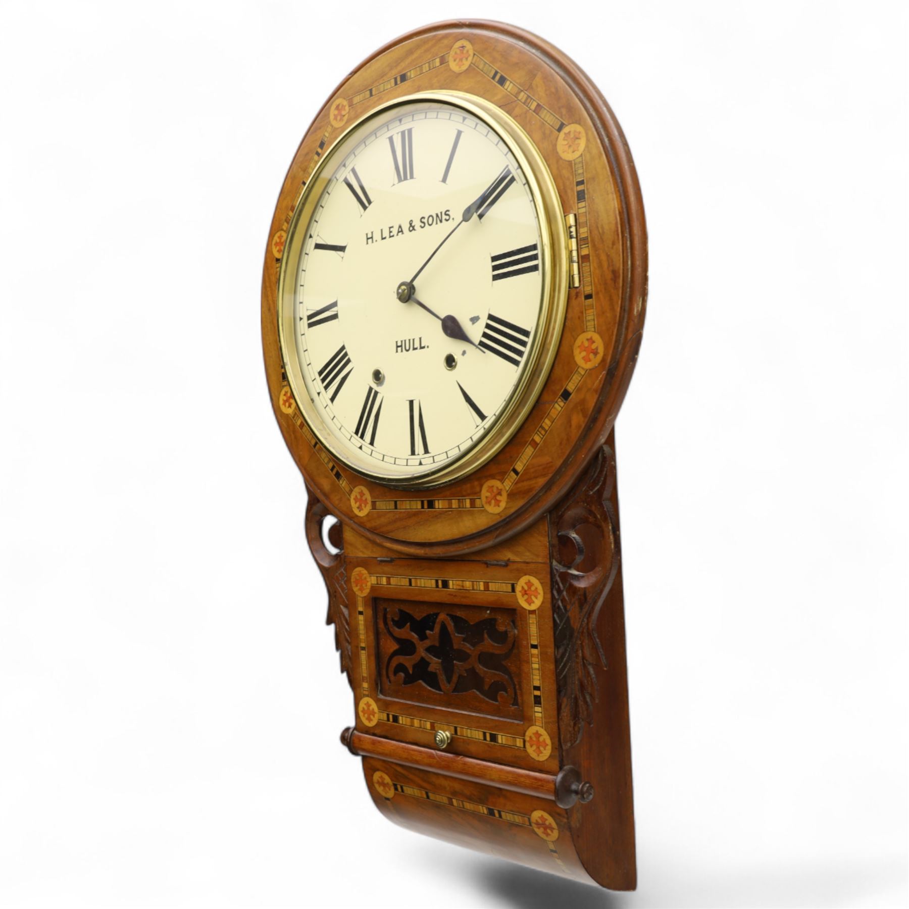 Lea & Son of Hull-American 8-day inlaid mahogany wall clock, with a curved base and carved ears flanking a glazed case door with open fretwork, 12” painted dial with Roman numerals, minute track and spade hands, spring driven movement with a countwheel strike, striking the hours on a bell. With pendulum.
