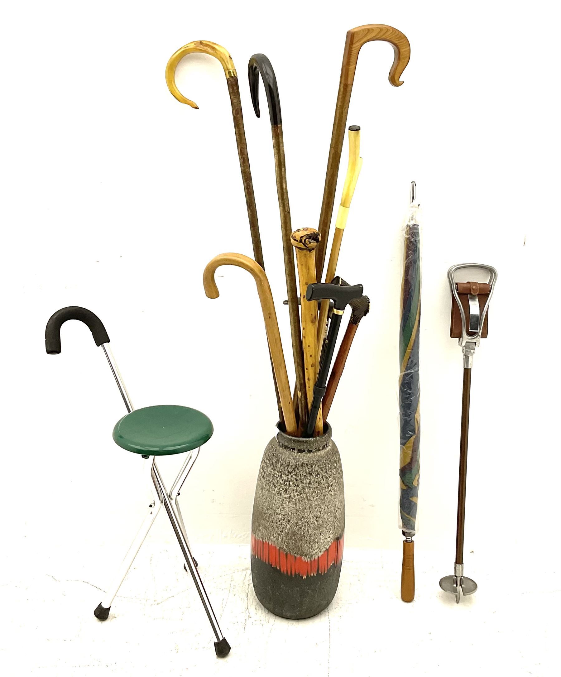 Two smooth polished ram horn handled Shepherd's crooks and a further similar example, together with various shooting sticks, walking sticks and canes, housed in a volcanic lava glaze West German style vase