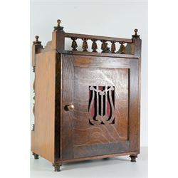 German -  late 19th century Arts and Crafts oak cased 8-day mantle clock, light oak case with a clear polished grain, flat top with gallery  to the rear and turned wooden finials, glazed door to the front flanked by two turned pilasters, rear case door with a silk backed lyre sound fret, brass dial with matted centre and cast spandrels, silvered chapter ring with Roman numerals and fleur di Lis steel hands, polished square movement plates with a twin train count wheel striking movement sounding the hours and half hours on a coiled gong. With pendulum and key.