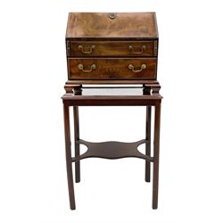 Georgian figured mahogany miniature bureau on stand - the fall front bureau with well fitted interior featuring a combination of thirteen sliding parts, central mirrored fret work door with leading chequered inlaid steps, flanked by a series of bricked arches and Doric columns, fitted with two drawers, the lower drawer with star inlay, lower moulding over ogee bracket feet, brass carrying handle to each side. The stand in figured mahogany with moulded lipped top, square supports with outer mould and inner chamfer joined by shaped undertier