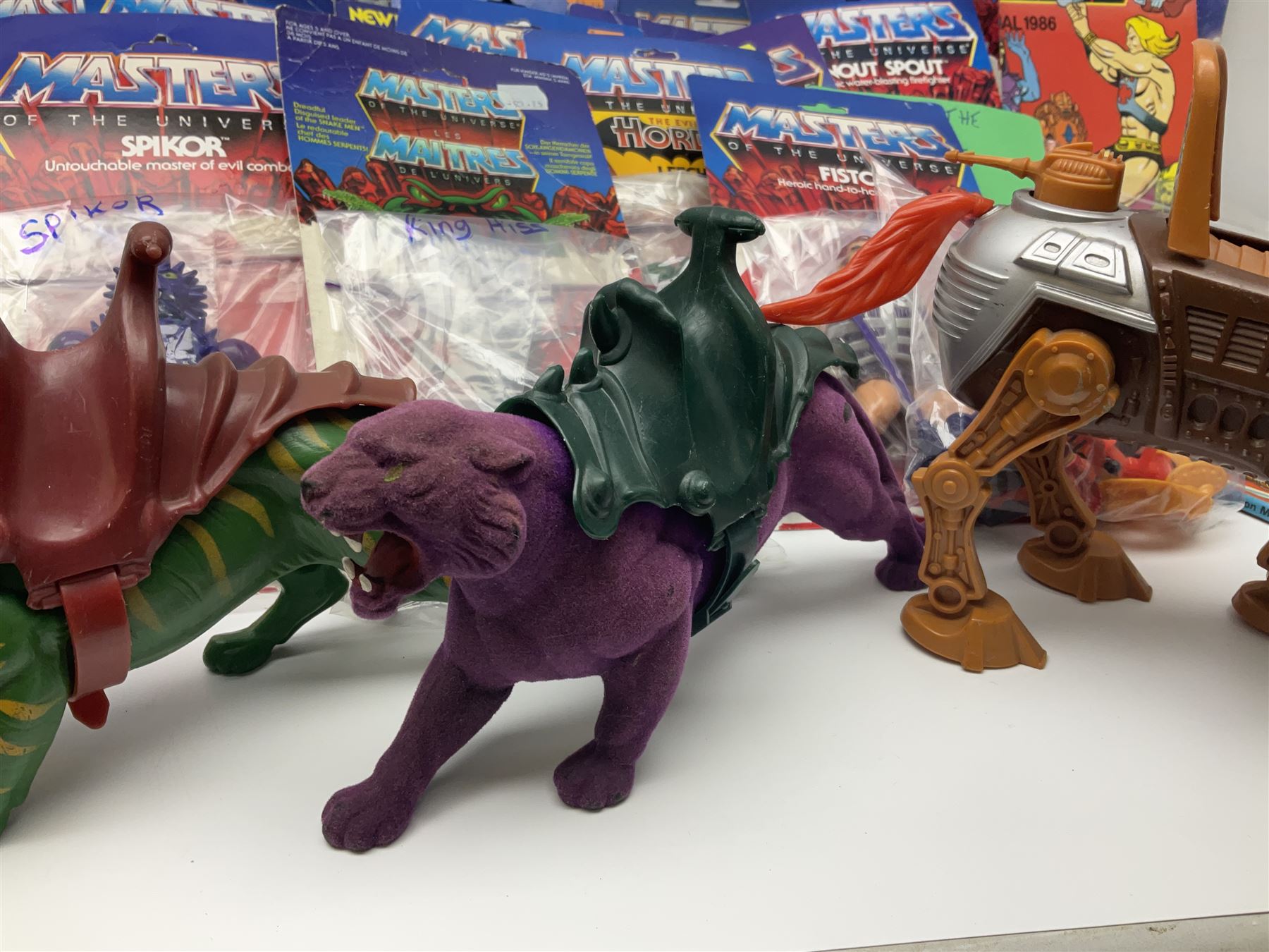 Thirty-one Masters of the Universe He-Man figures re-bagged on original backing cards;  two others lacking backing cards; boxed Modulok figure; bag of weapons and accessories; Roton, two horses and two battle cats; 1986 & 1987 Annuals; Ladybird and other story books; Panini sticker album; instructions etc