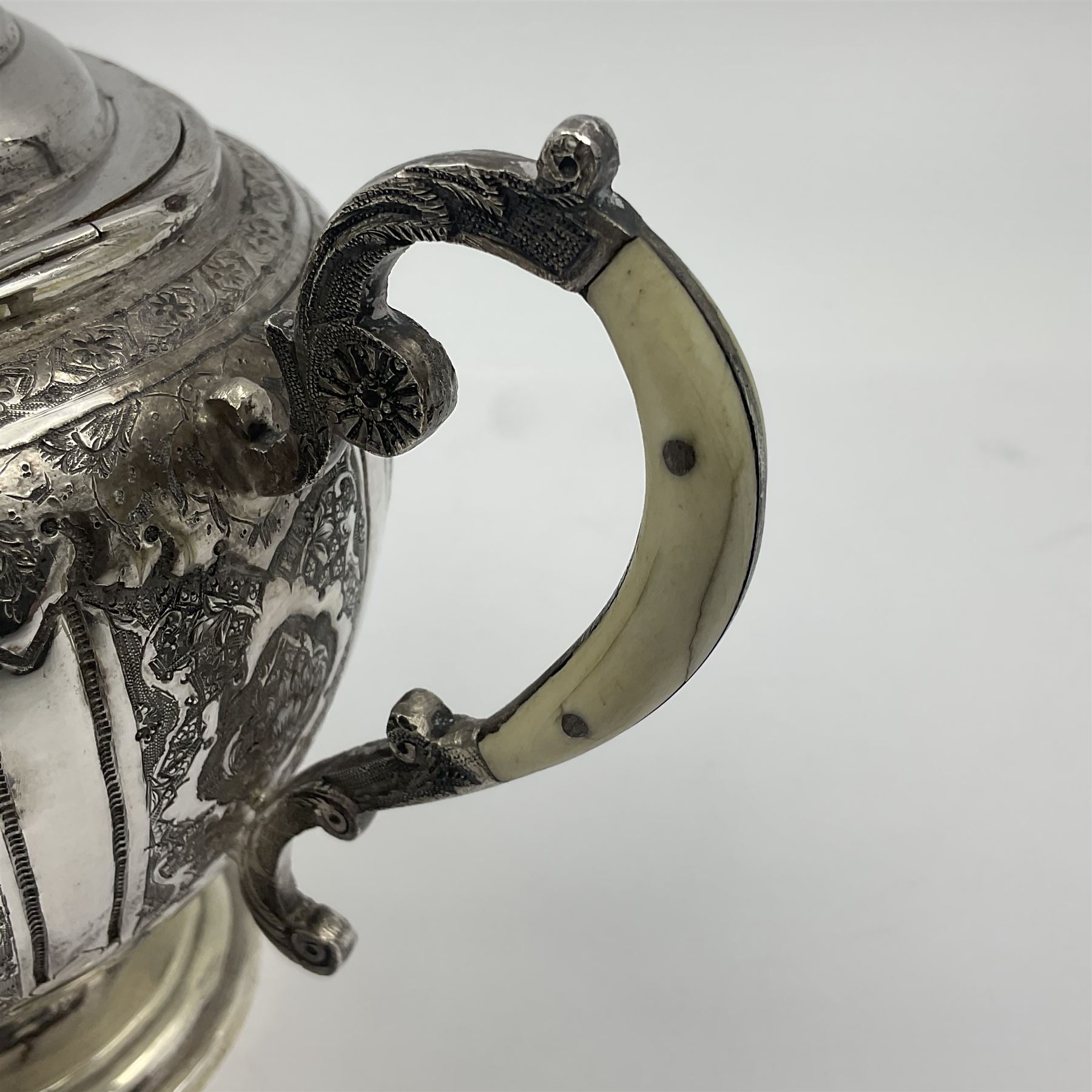 Early/mid 20th century Persian silver tea service, comprising circular serving tray, teapot, twin handled sucrier and cover, milk jug, five tea glasses with six silver holders, six tea spoons, and pair of sugar tongs, each profusely chased with foliate arabesque decoration, each bearing marks including 84 for 840 fineness, tray D40cm, teapot H16cm