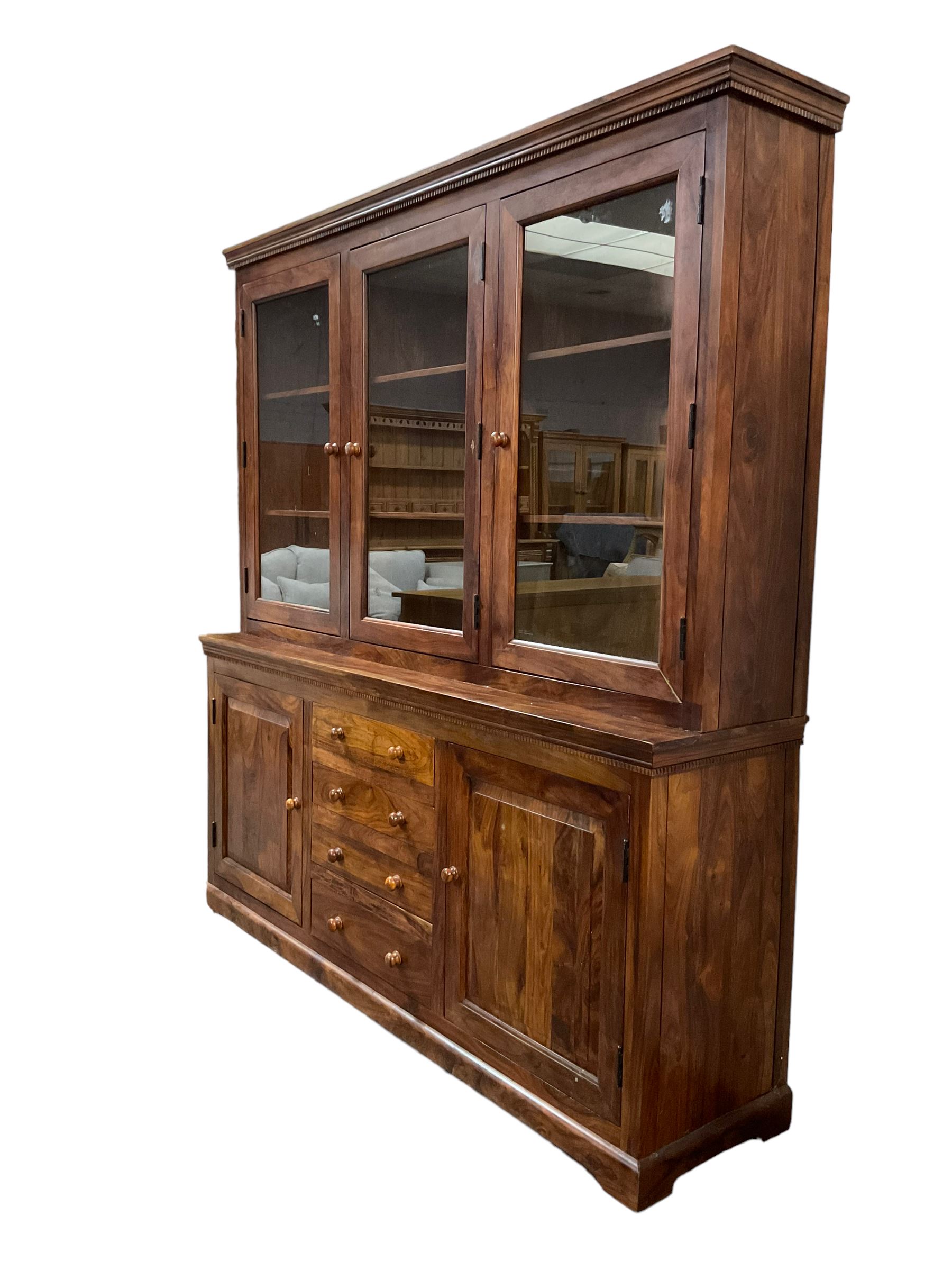 Large hardwood display wall unit, the upper section fitted with three glazed doors enclosing six shelves, the lower section fitted with four central drawers flanked by two panelled cupboards