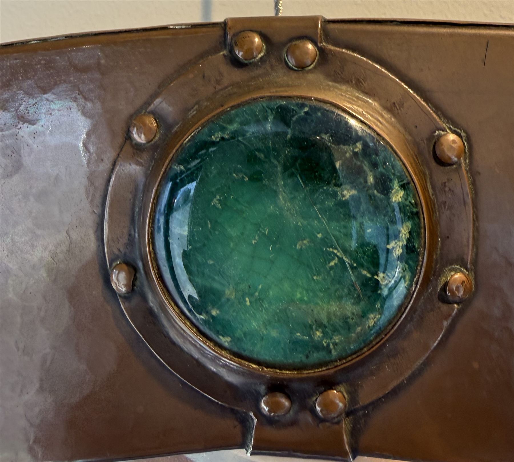 Liberty & Co, Arts and Crafts hammered copper framed oval wall mirror, mounted by four turquoise Ruskin cabochon roundels, with ivorine maker's label verso