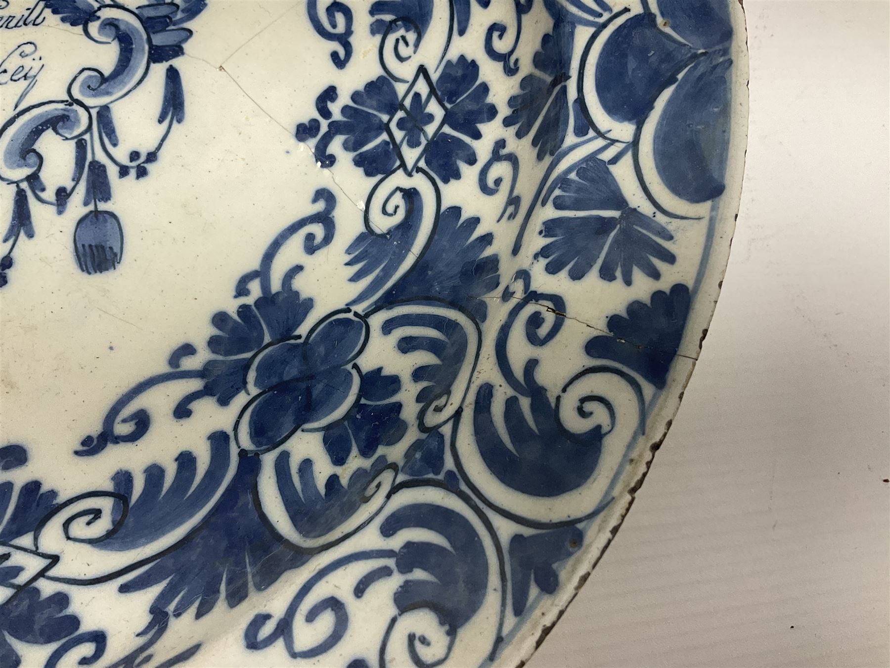 Early 18th century Delft marriage plate, of circular form with dished centre, the centre inscribed and dated 'Thomas and Elizabeth Kockerill Bridlington Key 1715' within a crowned C scroll cartouche, flanked by demi-griffins, above a putto head and tassels, within a wide foliate border, D34cm
