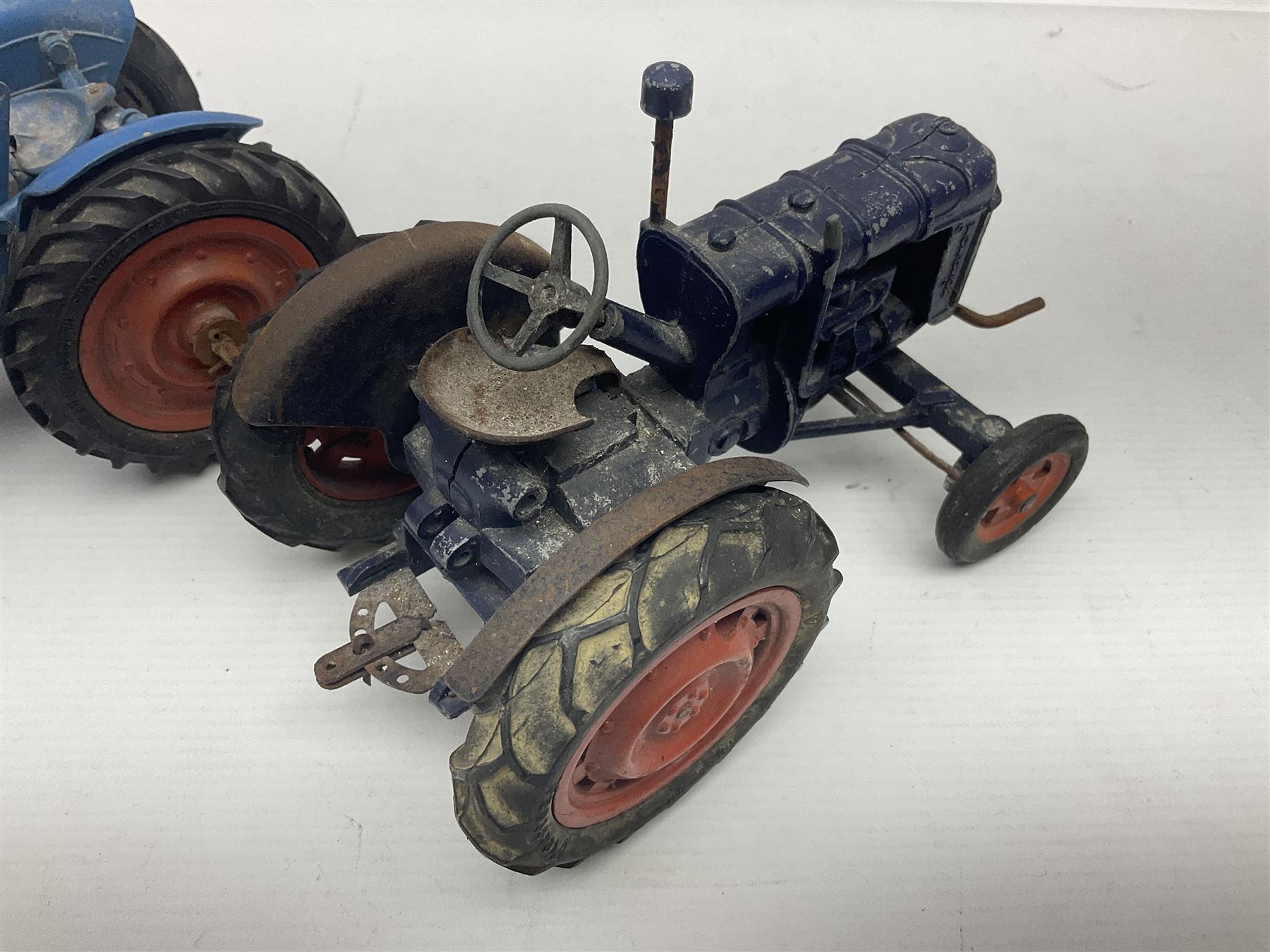 Chad Valley - two unboxed and playworn large scale Fordson tractors - No.9235 Fordson Major Tractor, dark blue diecast body, orange wheels, crank handle clockwork mechanism and 'Firestone' rubber tyres; and No.M59 New Fordson Major Tractor, blue diecast body, tinplate hinged bonnet, orange wheels and clockwork motor contained in rear wheel hub (2)