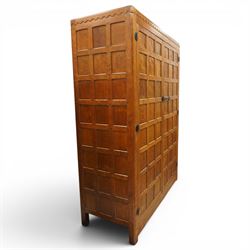 Mouseman - early-to-mid-20th century figured panelled and adzed double wardrobe of large proportions, the arcade carved cresting rail over two doors with adzed and figured oak panels, with wrought metal hinges and latch, relief carved mouse signature, the interior fitted with hanging rail, by the workshop of Robert Thompson, Kilburn