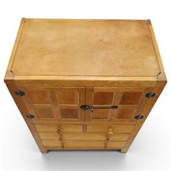 Mouseman - mid-20th century adzed and panelled oak tallboy chest, arcade carved cresting rail over two panelled cupboard doors with wrought iron fittings and latch, enclosing single shelf, over two short and two long drawers with lightly adzed facias and turned knob handles, raised on square supports, relief carved mouse signature, by the workshop of Robert Thompson of Kilburn