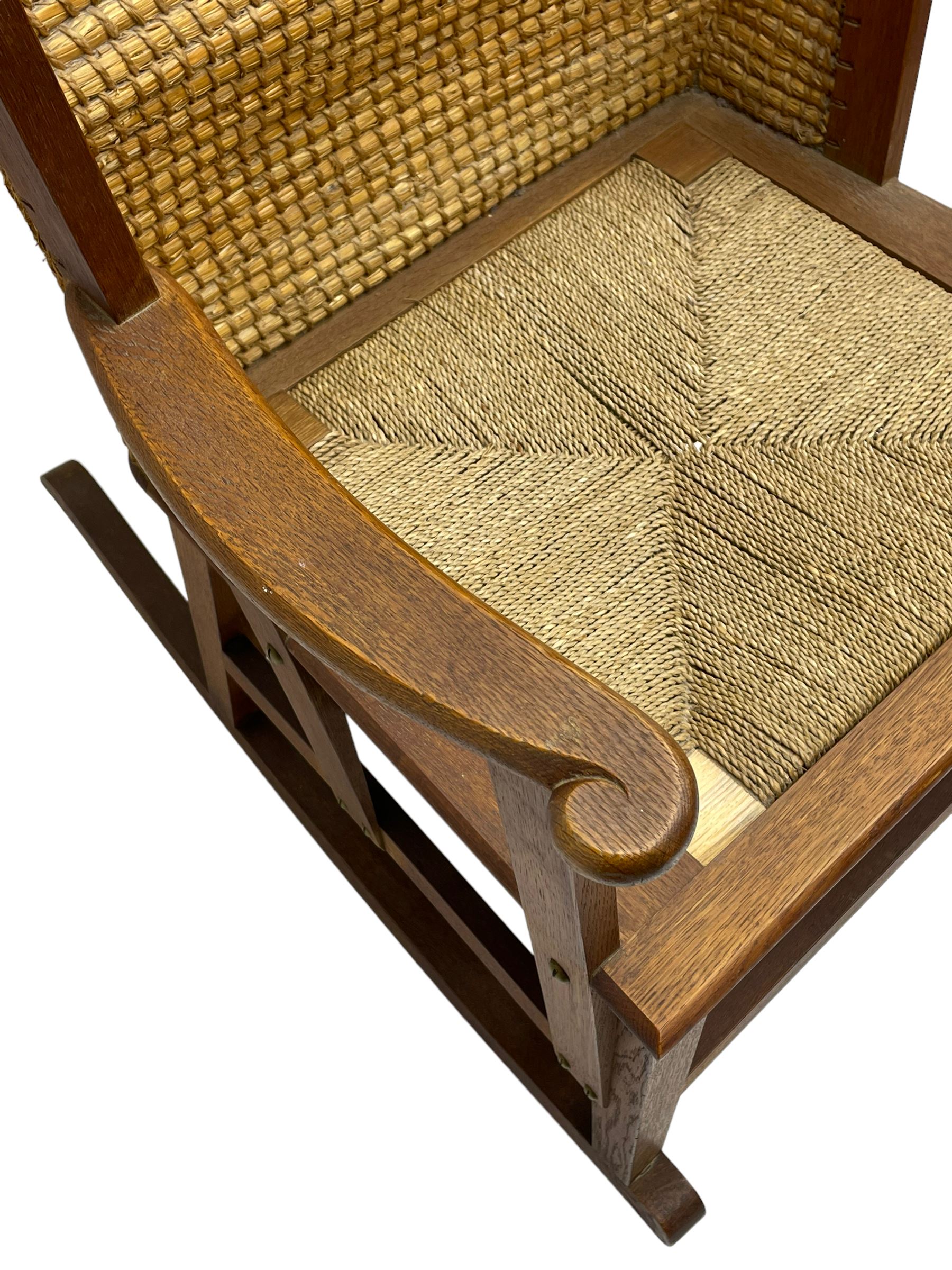 Reynold Eunson (1932–1978) for David Munro Kirkness, Kirkwall, Orkney - oak framed Orkney rocking chair, woven straw curved back, drop-in rush seat, the arm terminals with carved end scroll, on square tapering supports joined by plain stretchers, the front rail inscribed with makers marks