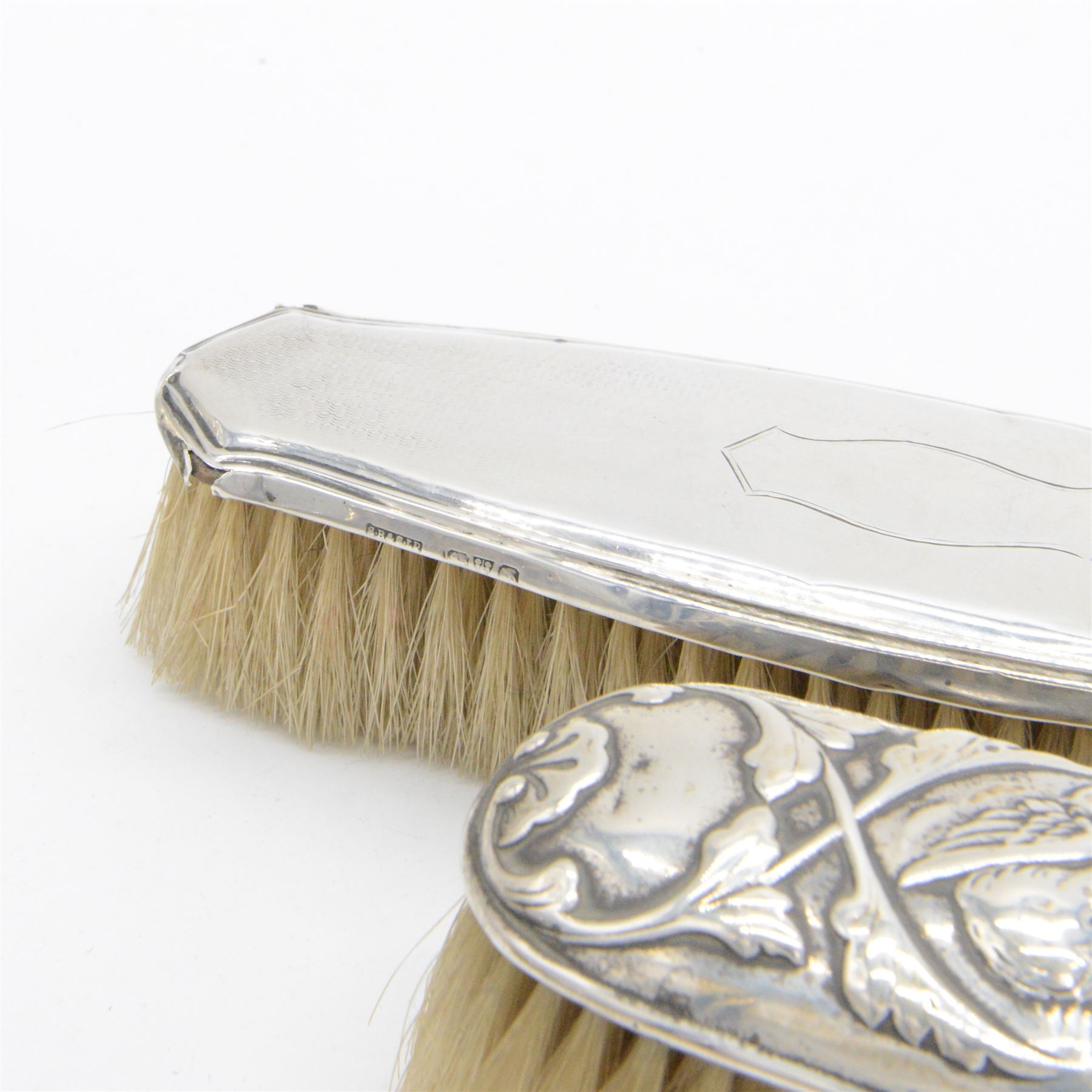Group of silver mounted dressing table items, to include dwarf candlestick, with embossed ribbon decoration, comb holder, jar lid and six clothes brushes, all hallmarked 