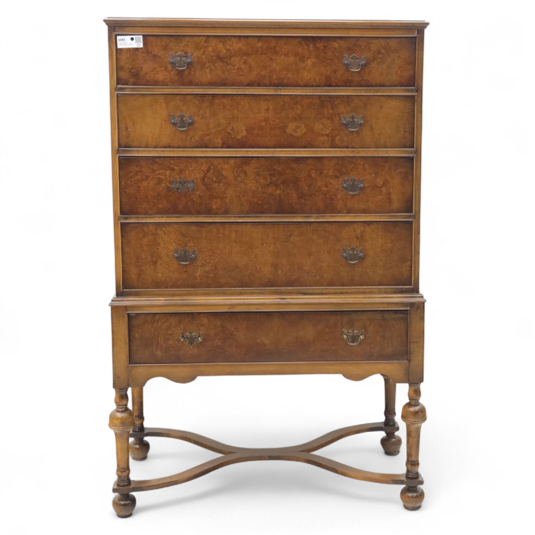 Georgian style walnut chest on stand, the figured top section fitted with four long drawers above a further drawer on the base, brass swan-neck handles, on turned legs joined by shaped stretchers with bun feet
