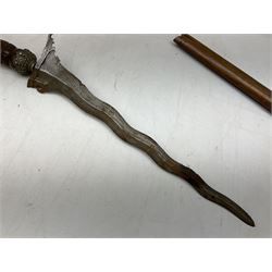 Malayan Kris with 36cm typically wavy blade with cast metal mounted carved hardwood handle L46.5cm overall; a similar kris with 35cm wavy blade and brass mounted carved hardwood handle; and another with 49cm oval section straight blade; all in wooden sheaths (3)