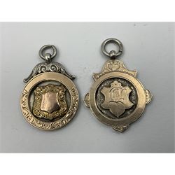 Seven early 20th century silver gold faced cartouche fobs, to include a circular example, with rose gold border and cartouche within an embossed yellow gold border, engraved verso, and a double sided example, all hallmarked with various dates and makers
