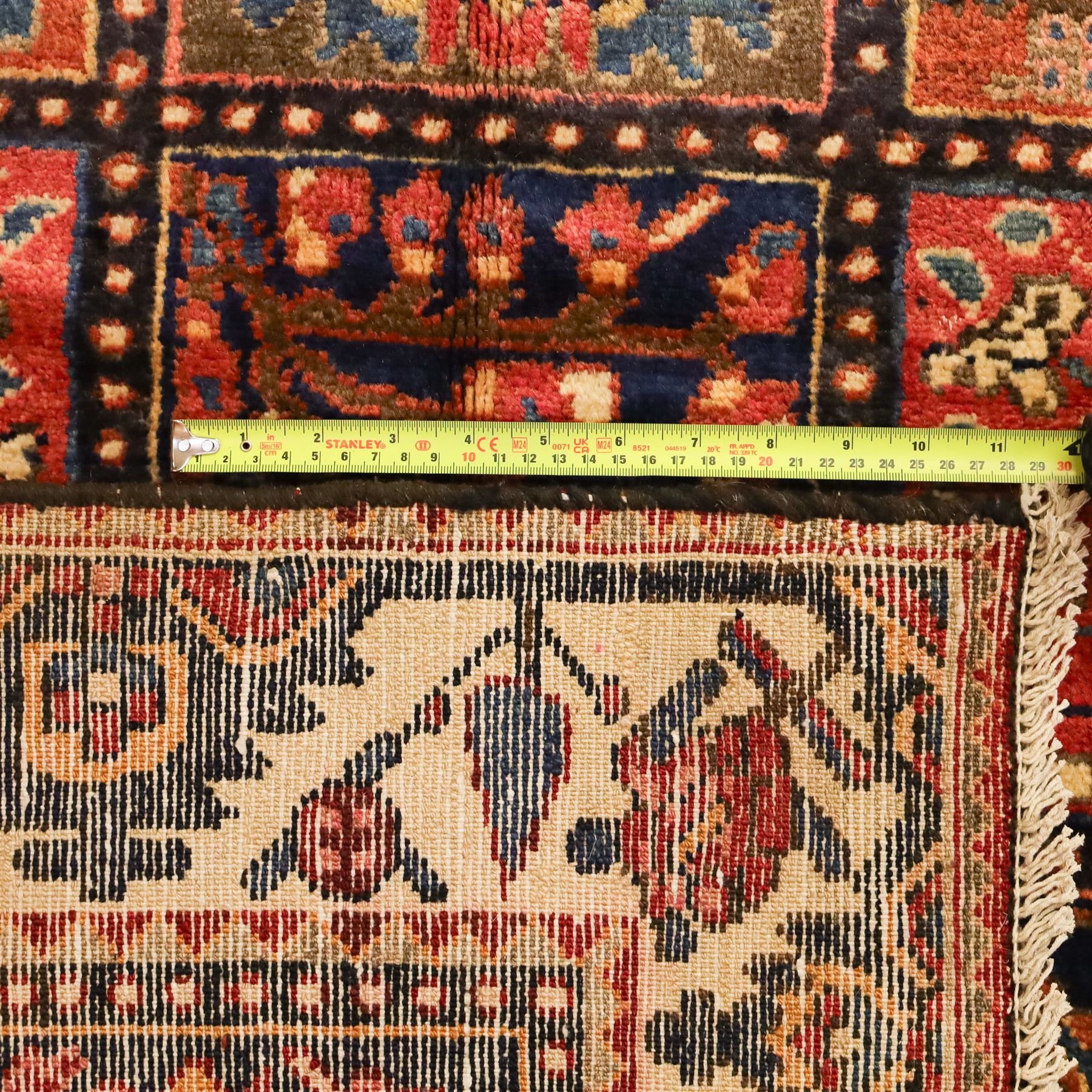 Central Persian Bakhtiari Kheshti design hand-knotted rug, field composed of a grid of square panels, each containing stylized floral devices, animal and foliate motifs woven in a rich palette of madder red, indigo blue, ivory ochre and brown, framed by a multiple striped border with a meandering vine and flowerhead band, with cotton fringe ends 