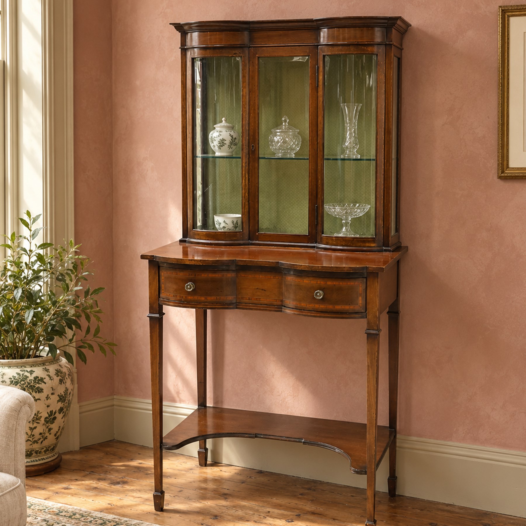 Edwardian inlaid mahogany serpentine-front side cabinet, raised back with central glazed door flanked by bow-front glass panels, the base fitted with banded and shaped frieze drawer, on square tapering supports united by concave under-tier