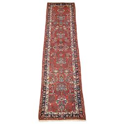 Persian runner rug, red ground field decorated with Herati motifs  and stylised flowers, the boarders and guards with trailing foliate decoration