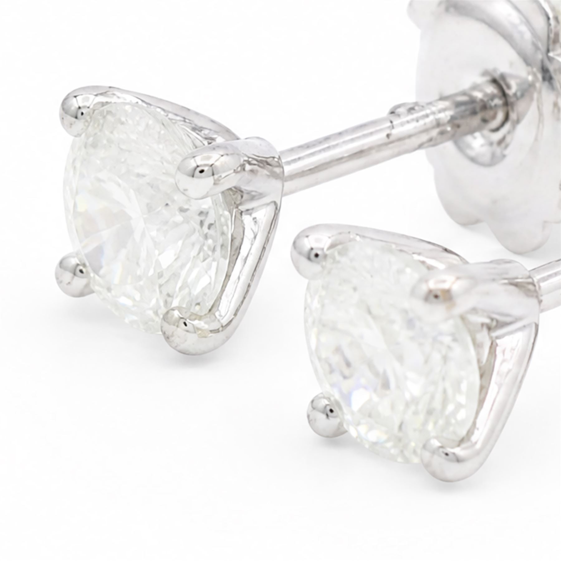 Pair of 18ct white gold diamond earrings, each stud four claw set with a single round brilliant cut diamond, stamped 750, total diamond weight approx 1.05 carat