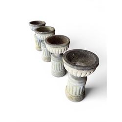 Four 20th century good quality weathered cast stone pedestal urns, circular lobed bowls with rope twist and lattice border, raised on squat base with fluted columns