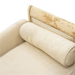 19th century French painted day bed, asymmetrical scrolled ends flanking a serpentine upholstered back, with upholstered end panels, loose seat cushions and cylindrical bolsters upholstered in beige fabric, with turned uprights with fluted detailing, moulded seat rail and lozenge-moulded corner blocks, raised on turned tapering supports