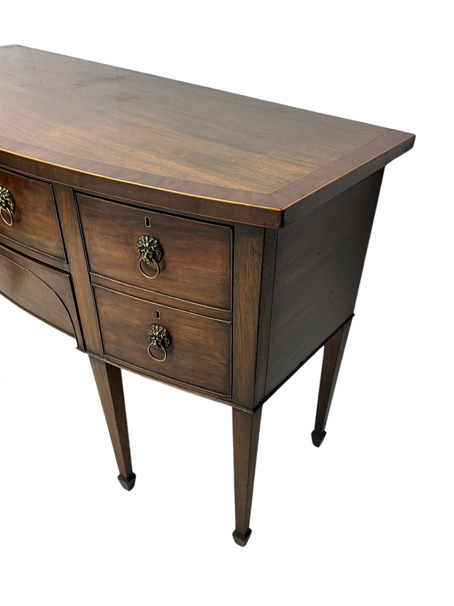 George III mahogany bow-fronted sideboard, mahogany banded top over three drawers and cupboard, fitted with lion mask and hoop handles, on square tapering supports with spade feet