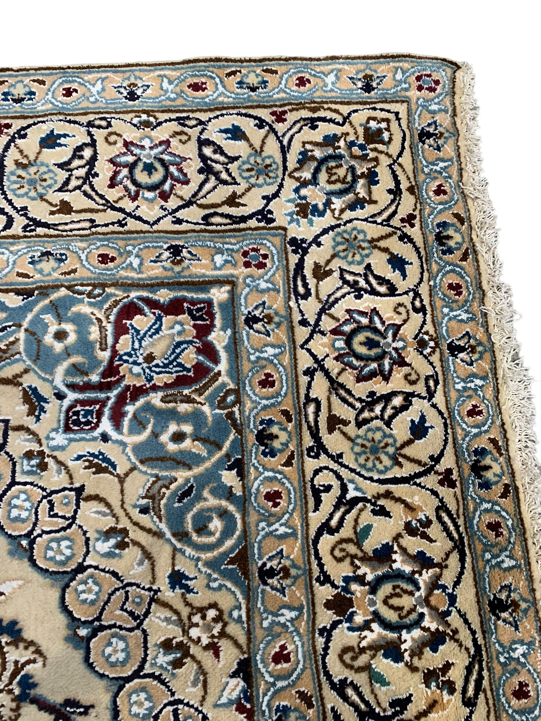 Persian Kashan ivory ground rug, central medallion surrounded by scrolling leafy branches and stylised flowerhead motifs, scrolling border decorated with further stylised plant motifs