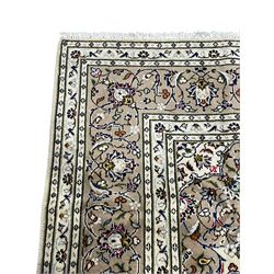 Persian Kashan ivory ground rug, central pointed rosette medallion surrounded by scrolling branches and stylised flower heads, the border with scrolling pattern decorated with palmettes, within guard stripes