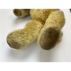 Merrythought Hygienic Toys large 'Magnet' teddy bear c1930s with plush body, swivel jointed head with glass eyes and vertically stitched nose and mouth and jointed limbs,  celluloid wishbone button to right ear and stitched label under right pad H22