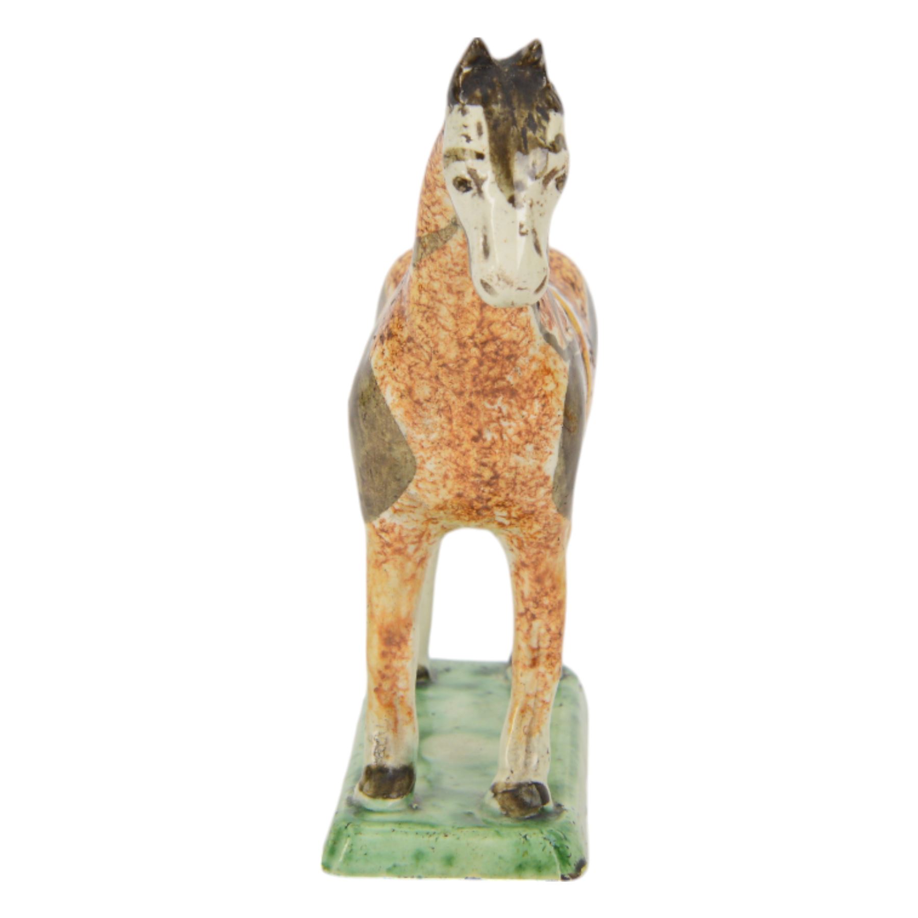 Late 18th/early 19th century Prattware pottery figure of a horse, possibly Yorkshire Potteries, circa 1790-1800, painted and sponge decorated in manganese, with blue spotted saddle secured with a yellow girth, upon a rectangular green base, H15.5cm