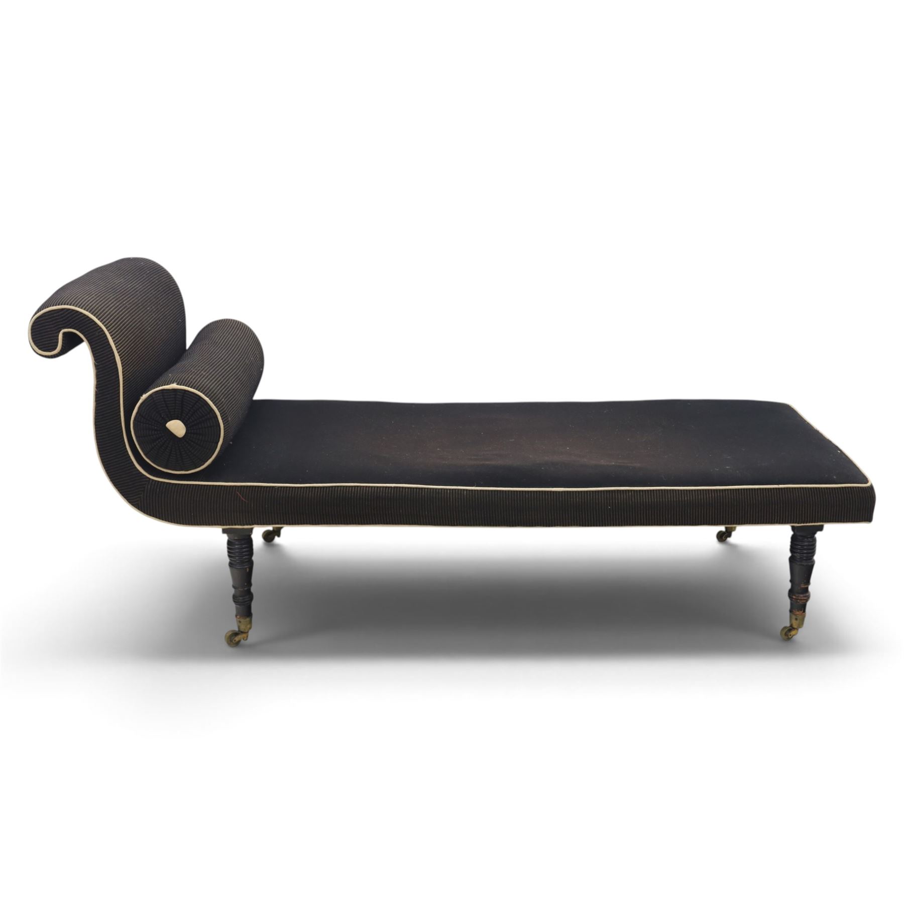Victorian ebonised chaise longue, upholstered in black fabric with scroll headrest and bolster cushion, rectangular seat with rounded corners, raised on turned supports terminating in brass and ceramic castors