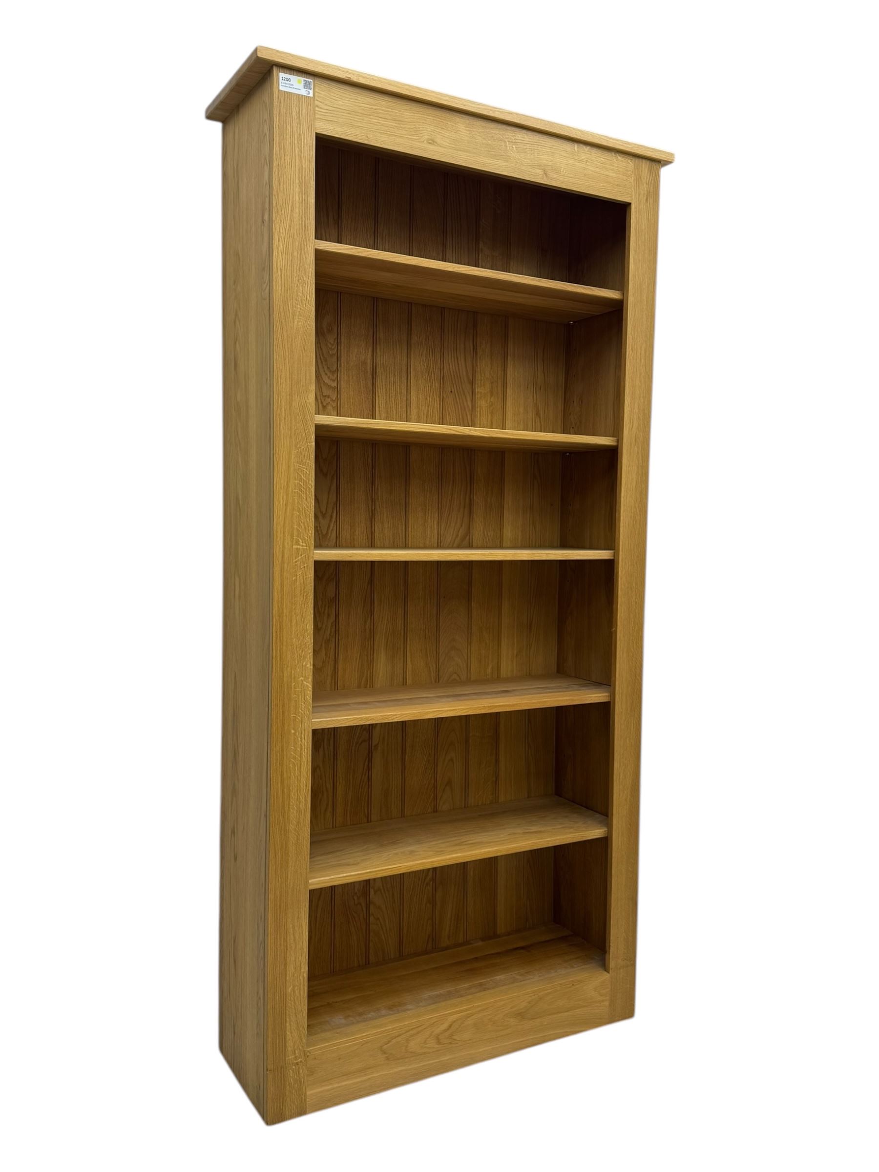 Contemporary light oak open bookcase, rectangular form with projecting top, fitted with five adjustable shelves, on a straight plinth base